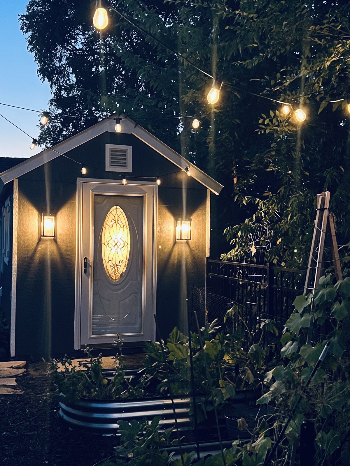 The studio shed at night, lit with string lights
