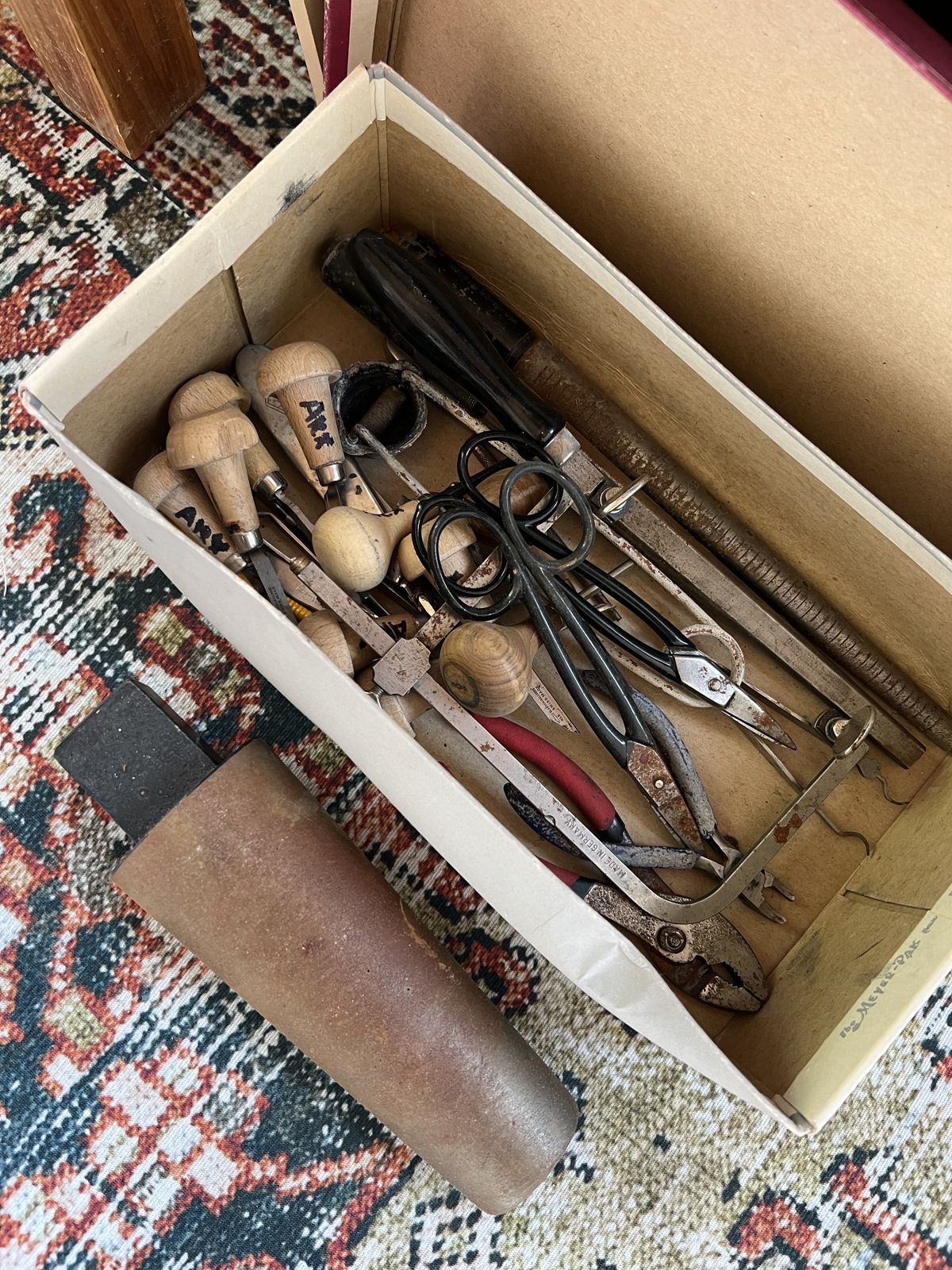 A box of old hand tools laid out on a rug